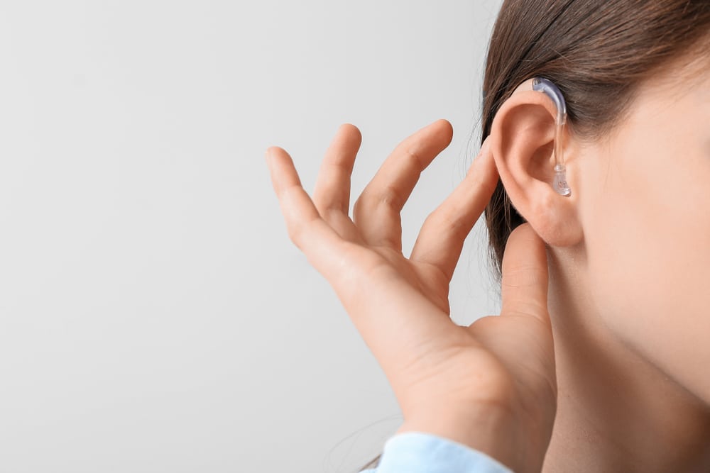 A close-up shot of a woman wearing a hearing aid in her ear